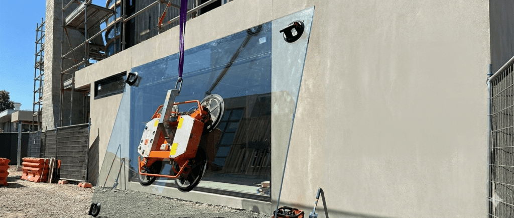 Glazier using vacuum lifter to install large glass panel